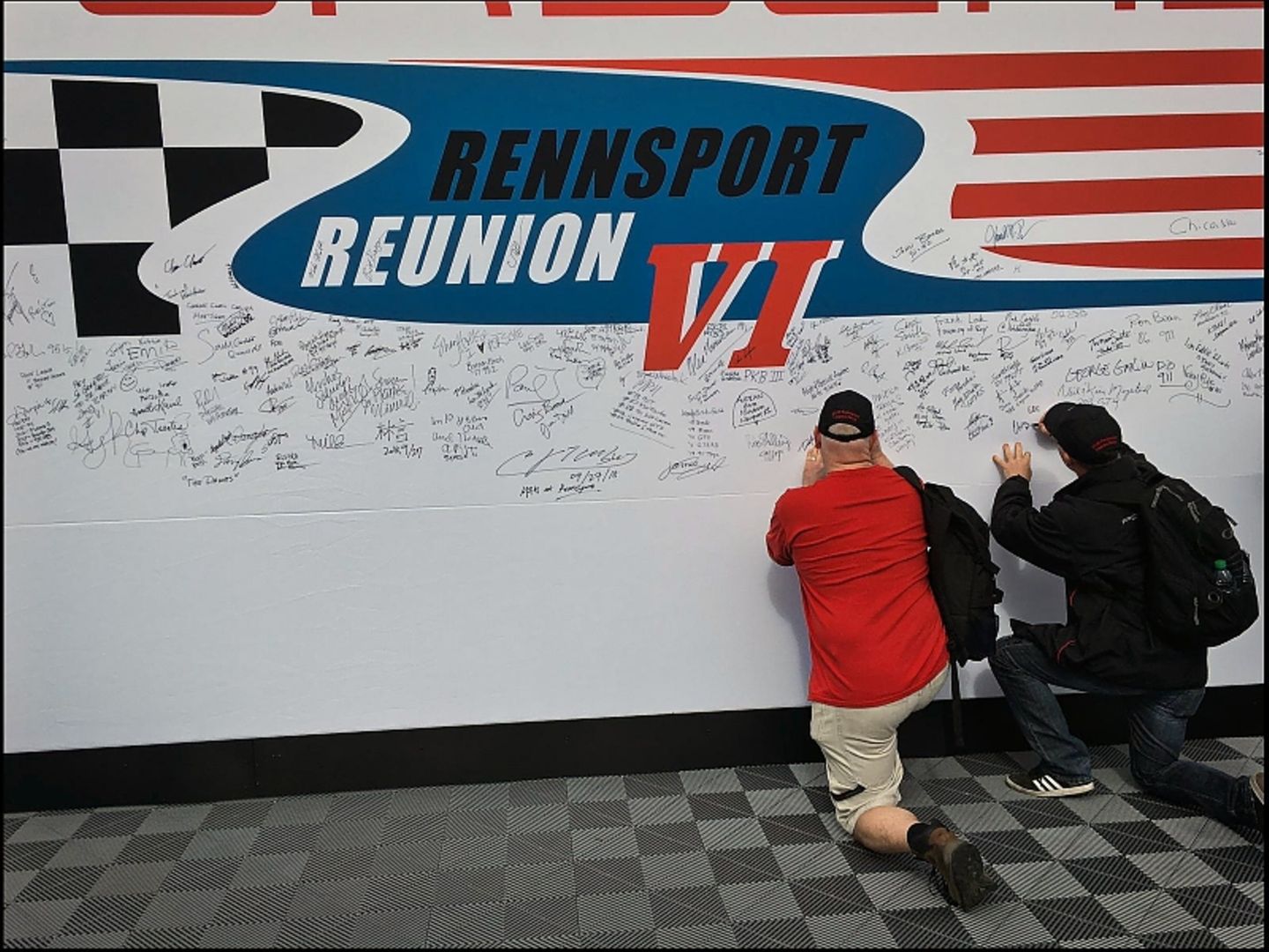 Bei der Porsche Rennsport Reunion 2018 kann sich jeder mit Gruß und Unterschrift auf einer großen Wandfläche verewigen