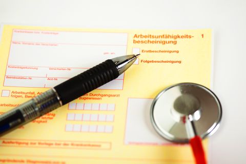 Auf einer Arbeitsunfähigkeitsbescheinigung liegt ein Stift