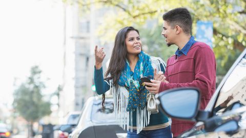 Ein Pärchen wartet am Straßenrand auf das Auto, das es telefonisch bestellt hat