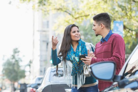 Ein Pärchen wartet am Straßenrand auf das Auto, das es telefonisch bestellt hat