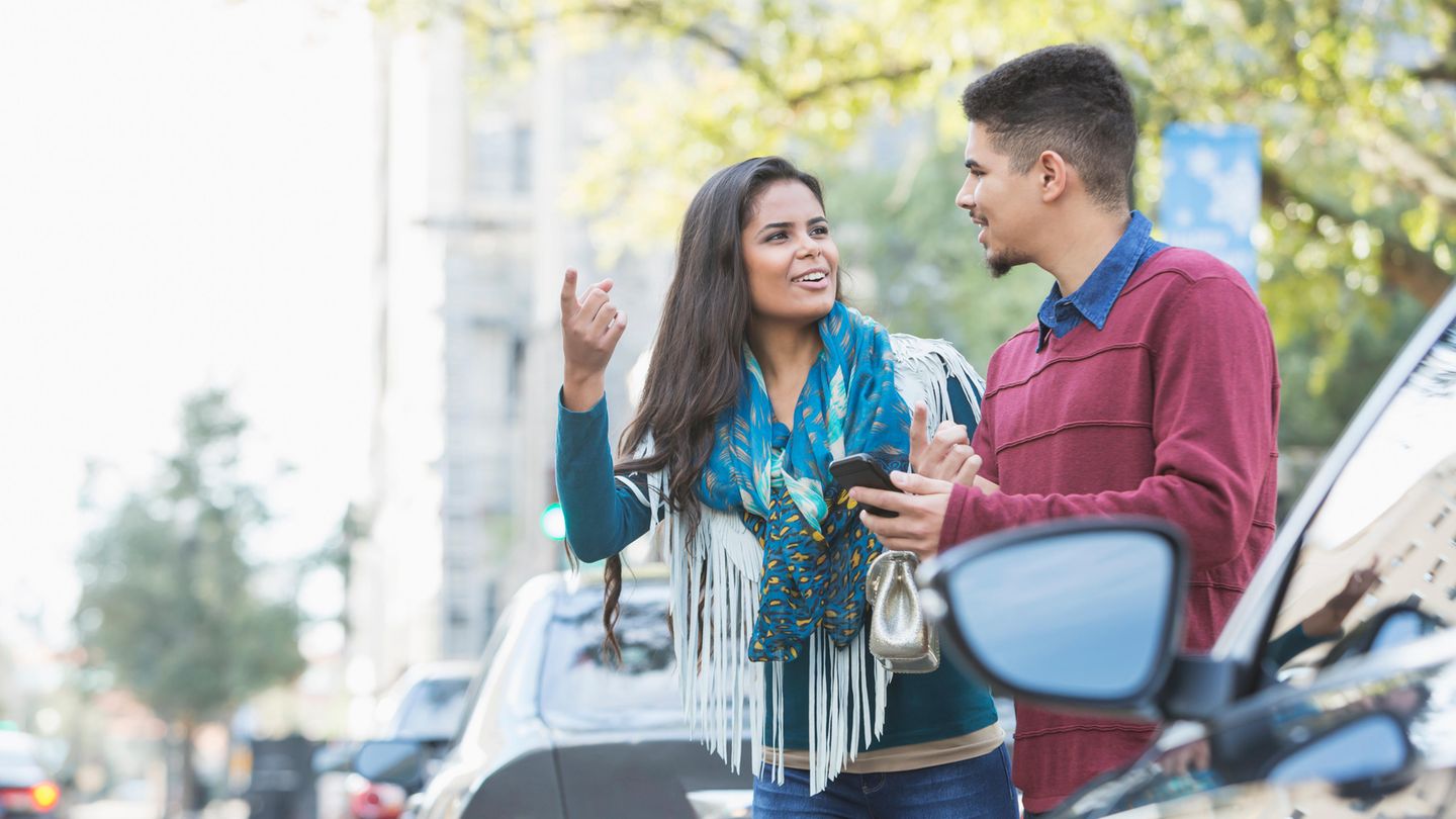 Ein Pärchen wartet am Straßenrand auf das Auto, das es telefonisch bestellt hat