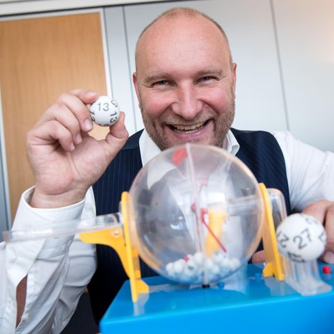 Rainer Holmer, Gewinnbetreuer von Lotto Bayern, sitzt in seinem Büro an einem Spielzeug-Ziehungsgerät für Lottokugeln