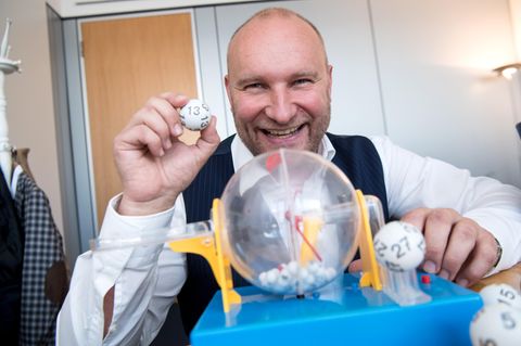 Rainer Holmer, Gewinnbetreuer von Lotto Bayern, sitzt in seinem Büro an einem Spielzeug-Ziehungsgerät für Lottokugeln