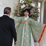 Für den Empfang kleidete sich Soyeon Kim in eine elegante, Hanbok genannte koreanische Tracht. Das bodenlange Kleid mit überlangen Ärmeln ist aus fließenden Stoffen kunstvoll gearbeitet, in mintgrün und weiß gehalten. An den Ärmeln ist ein gelb-roter Streifen abgesetzt, bedruckt ist die Tracht mit goldenen koreanischen Schriftzeichen.