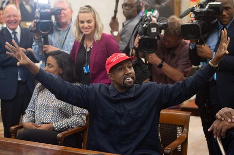 Rapper Kanye West beugt sich über den Schreibtisch von US-Präsident Donald Trump und zeigt ihm ein Foto auf dem Smartphone