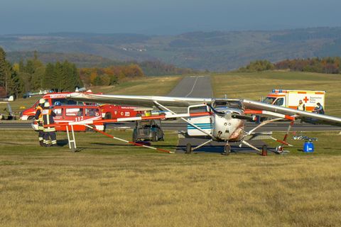 Feuerwehrleute stehen nach einem Flugunfall neben einem Sportflugzeug