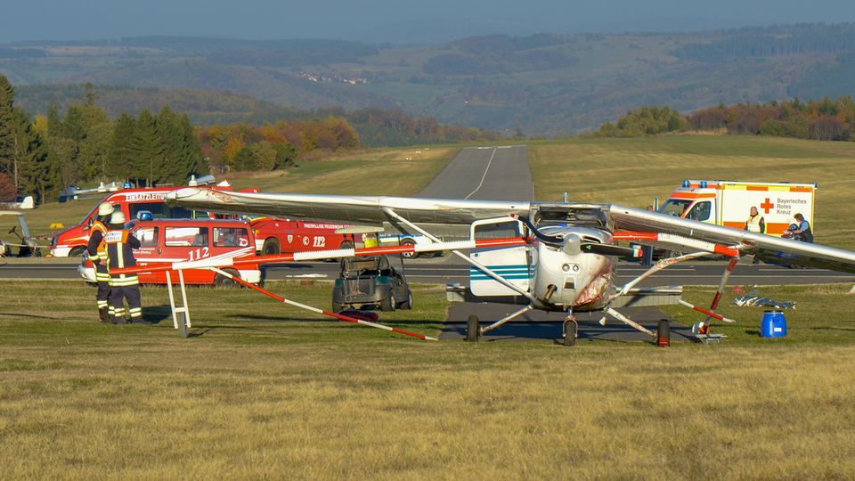 Feuerwehrleute stehen nach einem Flugunfall neben einem Sportflugzeug