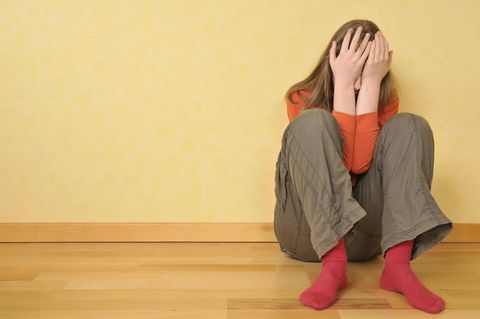 Eine schockierte 14-Jährige kauert am Boden