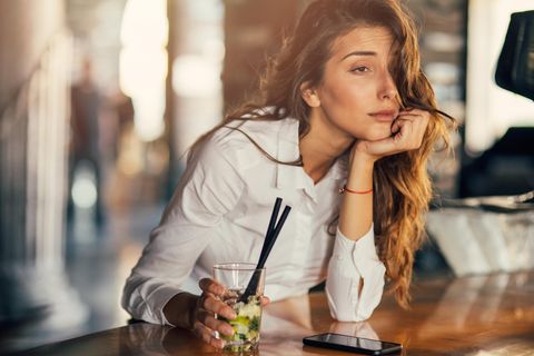 Eine Frau sitzt am Tresen und trinkt einen Cocktail