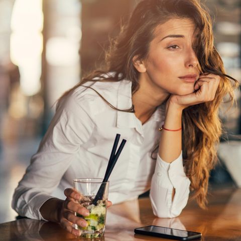 Eine Frau sitzt am Tresen und trinkt einen Cocktail