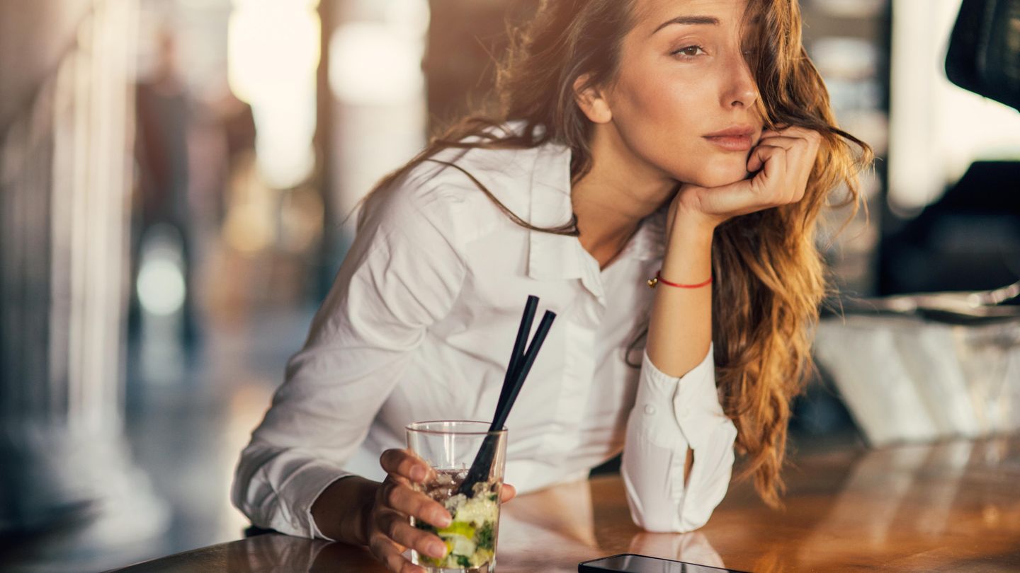 Eine Frau sitzt am Tresen und trinkt einen Cocktail