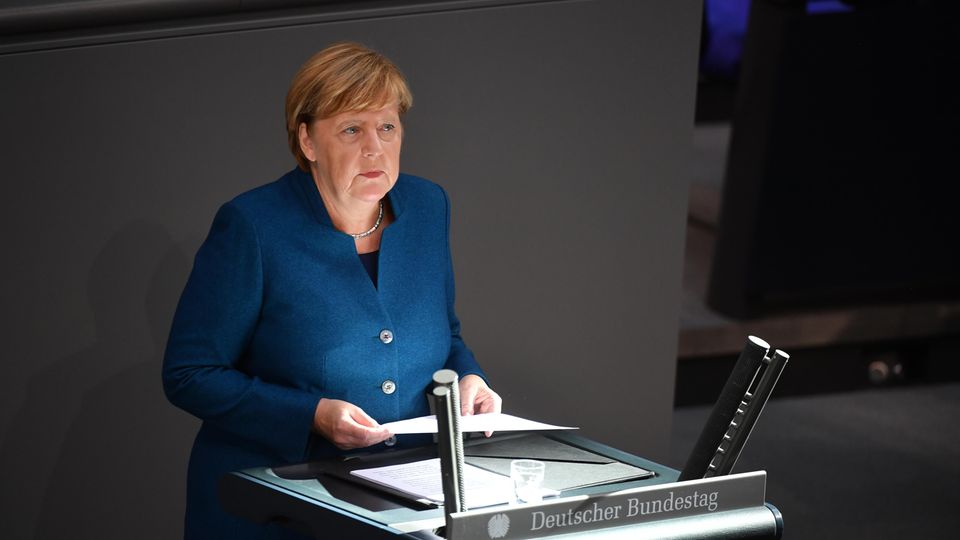 Bundeskanzlerin Angela Merkel steht am Rednerpult des Bundestages, auf das ein Sonnenstrahl trifft