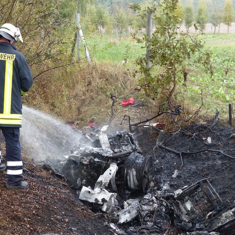 Ein Feuerwehrmann löscht die Überreste des ausgebrannten Ferraris  