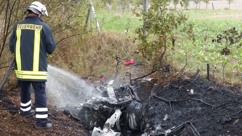 Ein Feuerwehrmann löscht die Überreste des ausgebrannten Ferraris  