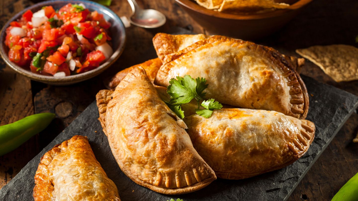 Bild 1 von 16 der Fotostrecke zum Klicken:  Empanadas sind Teigtaschen, gefüllt mit Schwein, Rind oder Pute, dazu Käse, Bohnenmus und auch gewürfelten Kartoffeln. Die Taschen werden in heißem Fett gebacken. Und gegessen werden sie meist ohne Besteck - sondern als "Snack to go".