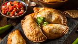 Bild 1 von 16 der Fotostrecke zum Klicken:  Empanadas sind Teigtaschen, gefüllt mit Schwein, Rind oder Pute, dazu Käse, Bohnenmus und auch gewürfelten Kartoffeln. Die Taschen werden in heißem Fett gebacken. Und gegessen werden sie meist ohne Besteck - sondern als "Snack to go".