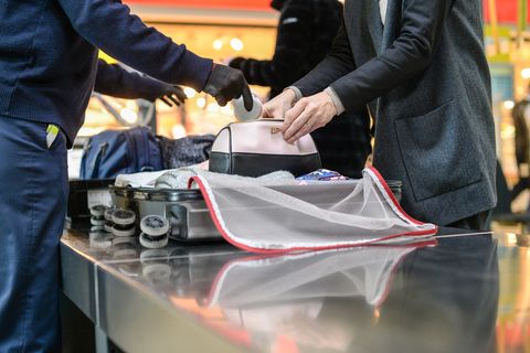 Ein Sicherheitsbeamter kontrolliert das Gepäck einer Reisenden am Flughafen