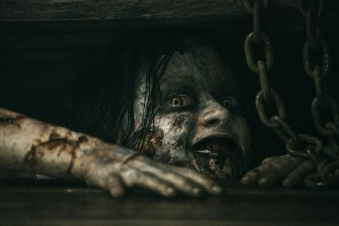 Gruselig aussehende Frau schaut aus einer Bodenluke