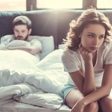 Frau sitzt an Bettkante