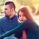 Frau sitzt mit Mann auf Wiese