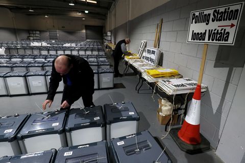 Ein Wahlhelfer bereitet in einer Halle die Wahlurnen vor