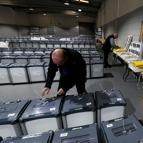 Ein Wahlhelfer bereitet in einer Halle die Wahlurnen vor