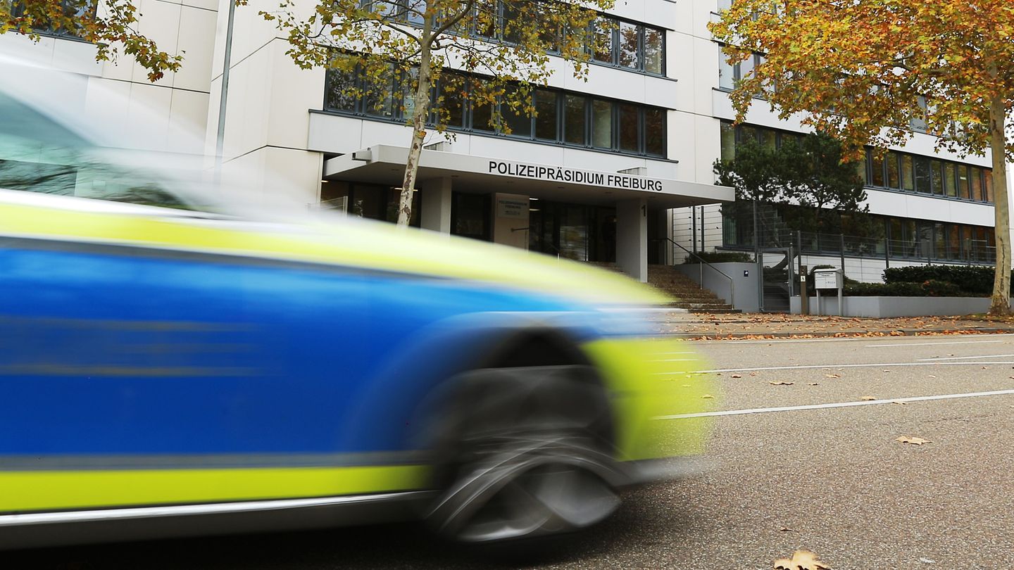 Vor dem Polizeipräsidium Freiburg fährt ein Polizeiauto vorbei. Das Auto ist wegen seiner Geschwindigkeit unscharf zu sehen