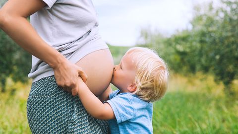 Ein kleiner Junge küsst den Bauch seiner schwangeren Mutter