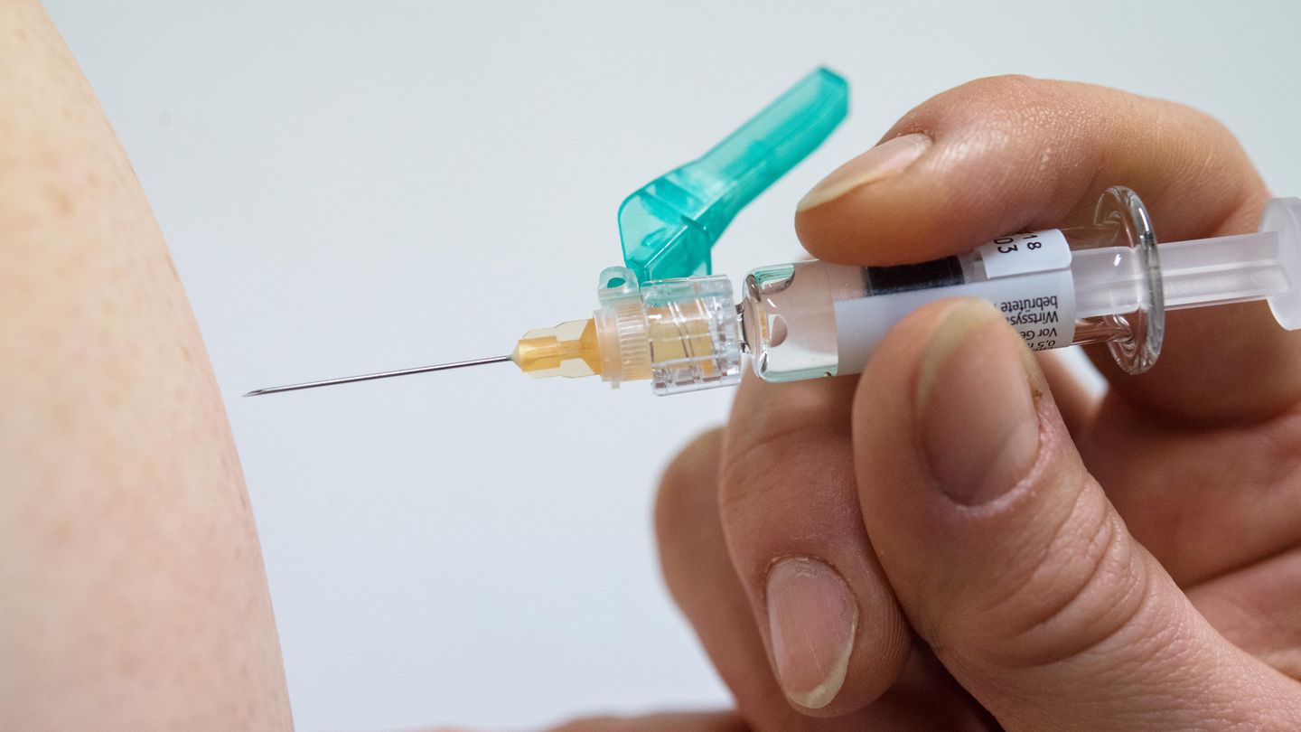 Ein Arzt impft eine Person gegen Grippe