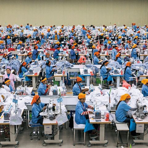 Einfache Näherinnen tragen orangefarbene Kopftücher, ihre Aufseherinnen lila. In der Textilfabrik Seduno am Stadtrand von Phnom Penh produzieren sie auch für C&A und H&M.
