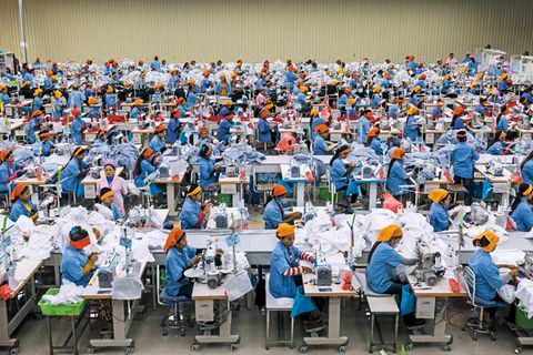Einfache Näherinnen tragen orangefarbene Kopftücher, ihre Aufseherinnen lila. In der Textilfabrik Seduno am Stadtrand von Phnom Penh produzieren sie auch für C&A und H&M.