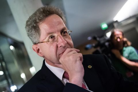 Hans-Georg Maaßen, ein Mann mit grauen Haaren und kleiner, goldener Nickelbrille, hält sich die rechte Hand vor den Mund