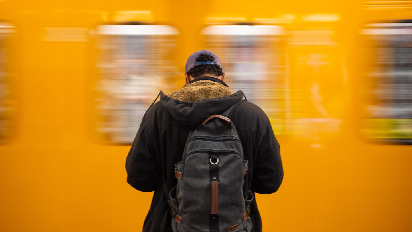 Ein Mann steht vor einer gelben U-Bahn in Berlin