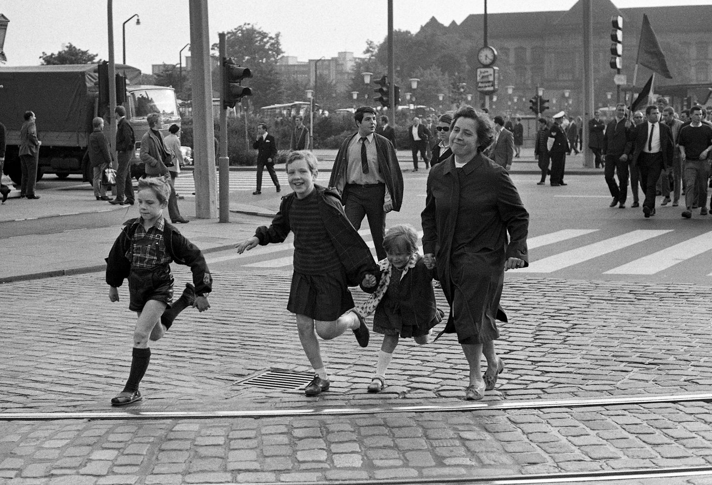 Eine Mutter rennt mit drei Kindern über die Straße