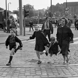 Eine Mutter rennt mit drei Kindern über die Straße