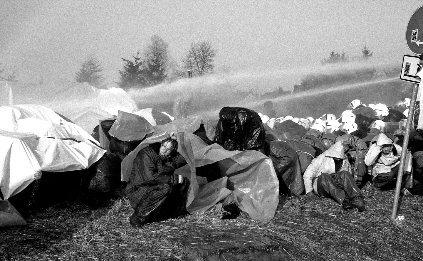 Demonstranten unter Planen gegen die Wasserwerfer