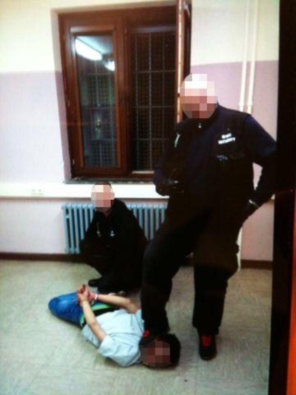 Zwei Männer posieren vor einem Mann, der am Boden liegt. Einer drückt seinen Fuß in den Hals des am Boden liegenden Mannes