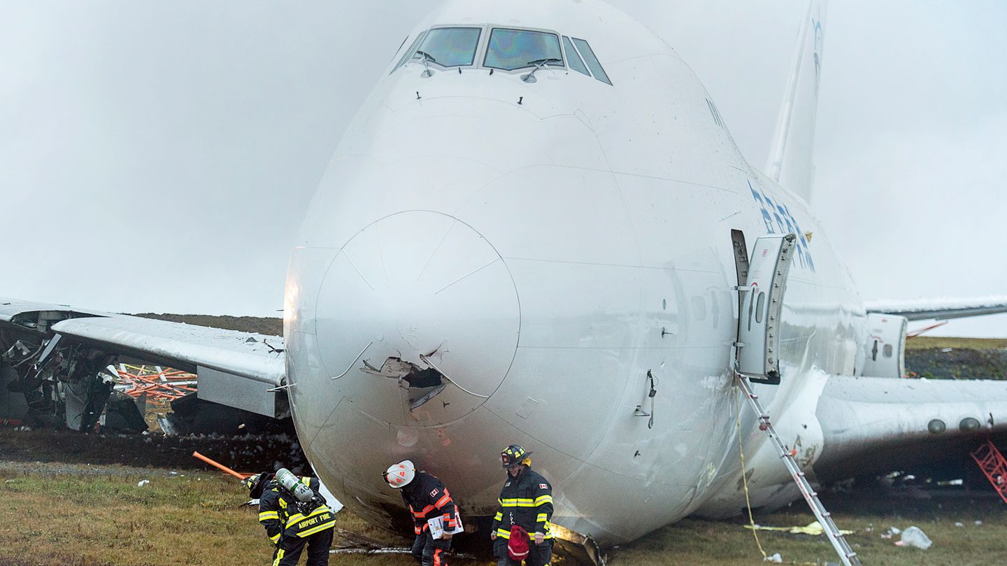 Rettungskräfte stehen vor einem Frachtflugzeug, das  von der Landebahn am Halifax Stanfield International Airport gerutscht ist.