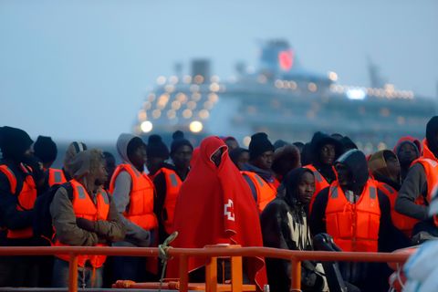 In rote Decken und Schwimmwesten gehüllte Migranten stehen nach ihrer Ankunft im Hafen von Malaga in Spanien. Viele Migranten, die übers Mittelmeer kommen, wollen nach Deutschland.
