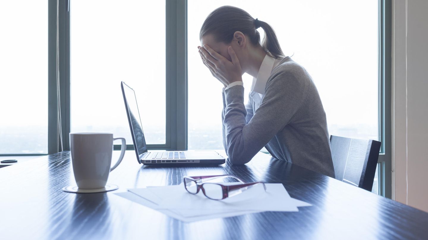 Eine Frau schlägt vor dem Laptop die Hände vor dem Gesicht zusammen
