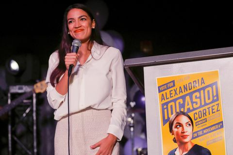 Alexandria Ocasio-Cortez steht auf der bühne und hält ein Mikrofon in der Hand