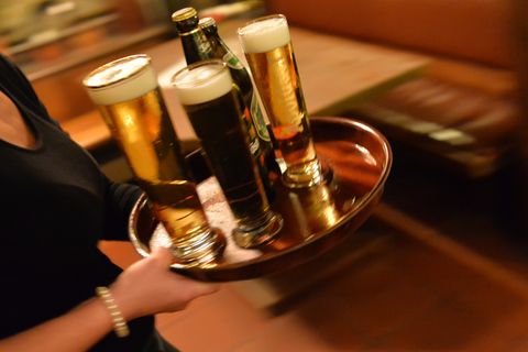 Kellnerin trägt Bier zum Gast