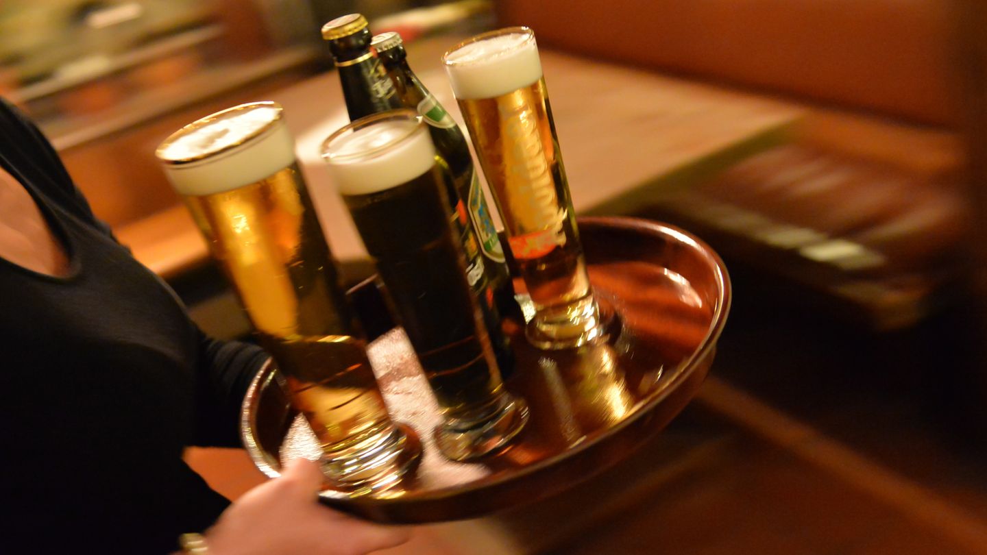 Kellnerin trägt Bier zum Gast
