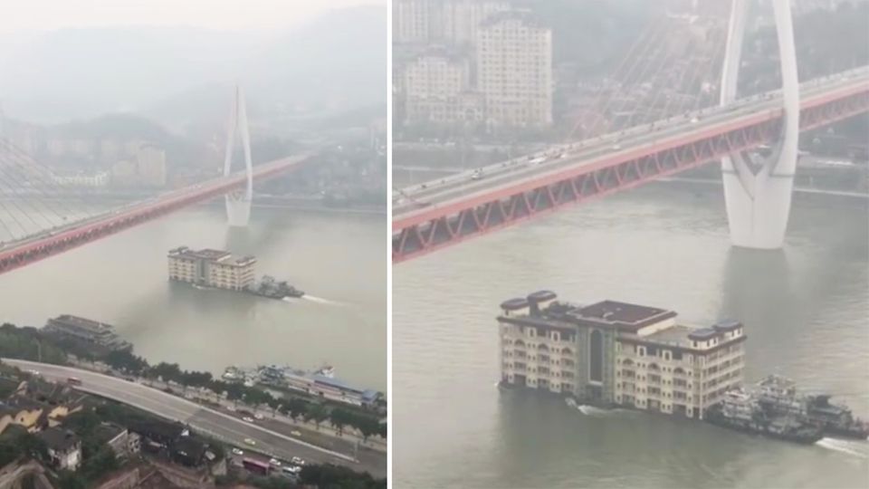 Zwei Schlepper schieben ein fünfstöckiges Hochhaus unter einer Brücke hindurch über den Yangtze in China.