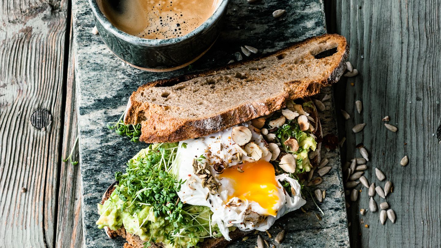 Avocado auf Röstbrot mit Nüssen, Sonnenblumenkernen, Ei, Kresse, Ducca und Kaffee