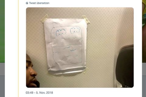 Ein Mann schläft im Flugzeug neben einem aufgemalten Fenster