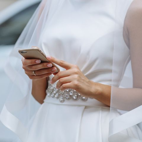 Eine Braut tippt auf dem Handy