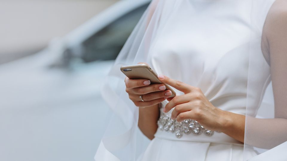 Eine Braut tippt auf dem Handy