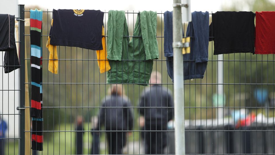 In einer Flüchtlingsunterkunft hängt Wäsche zum Trocknen über den Zaun