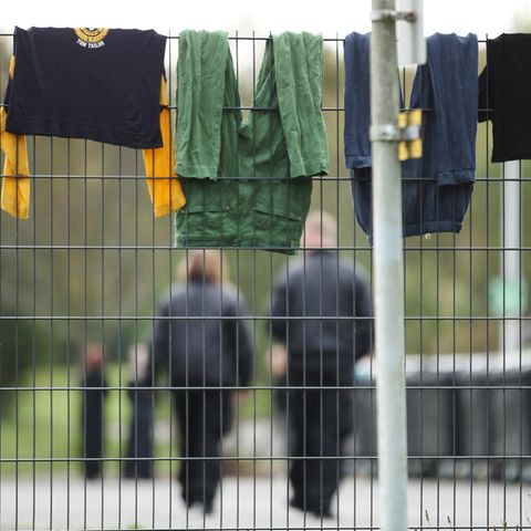 In einer Flüchtlingsunterkunft hängt Wäsche zum Trocknen über den Zaun
